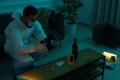 Forensic expert with camera taking photo of evidences at crime scene in dark room