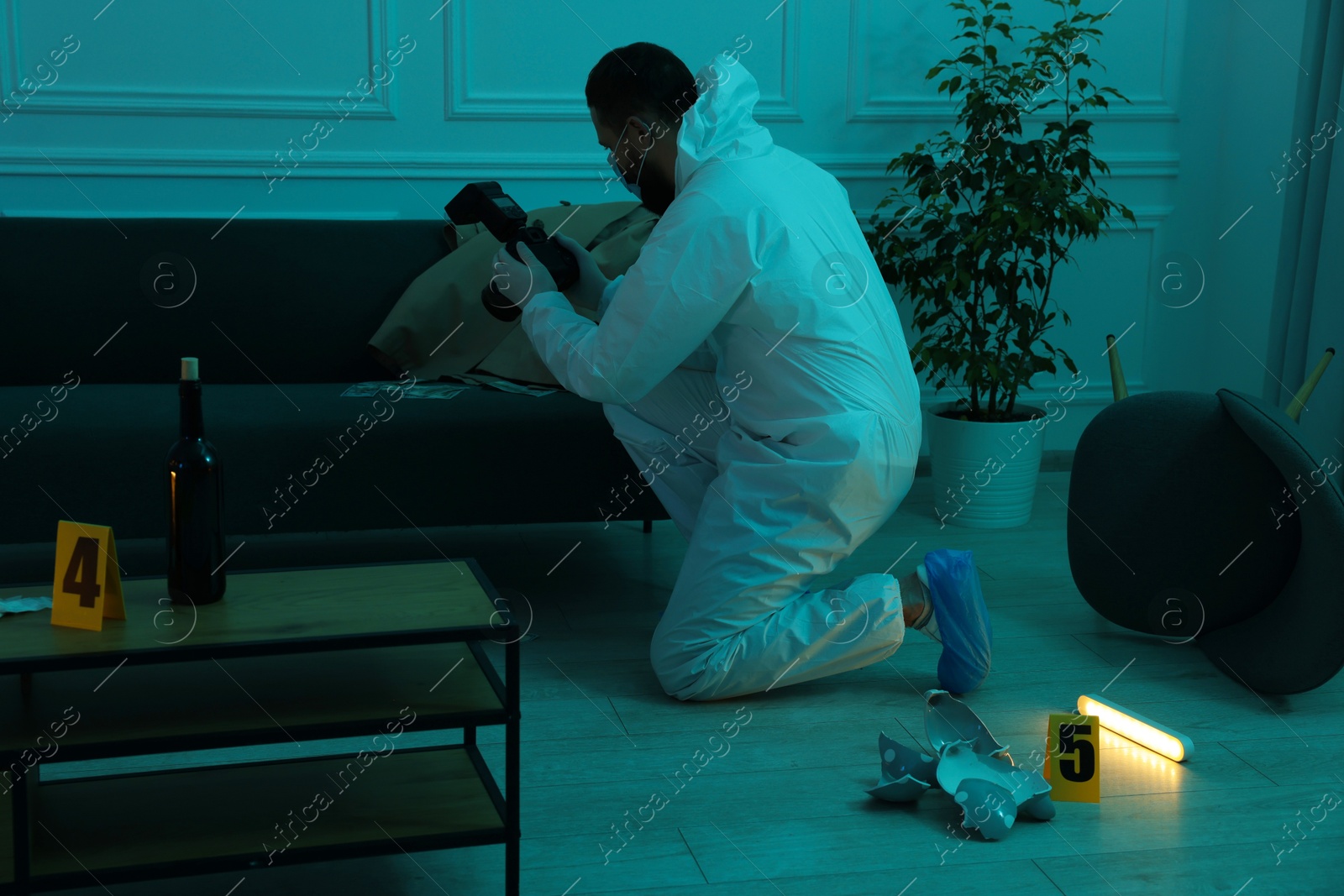 Photo of Forensic expert with camera taking photo of evidences at crime scene indoors