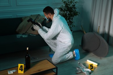 Forensic expert with camera taking photo of evidences at crime scene indoors