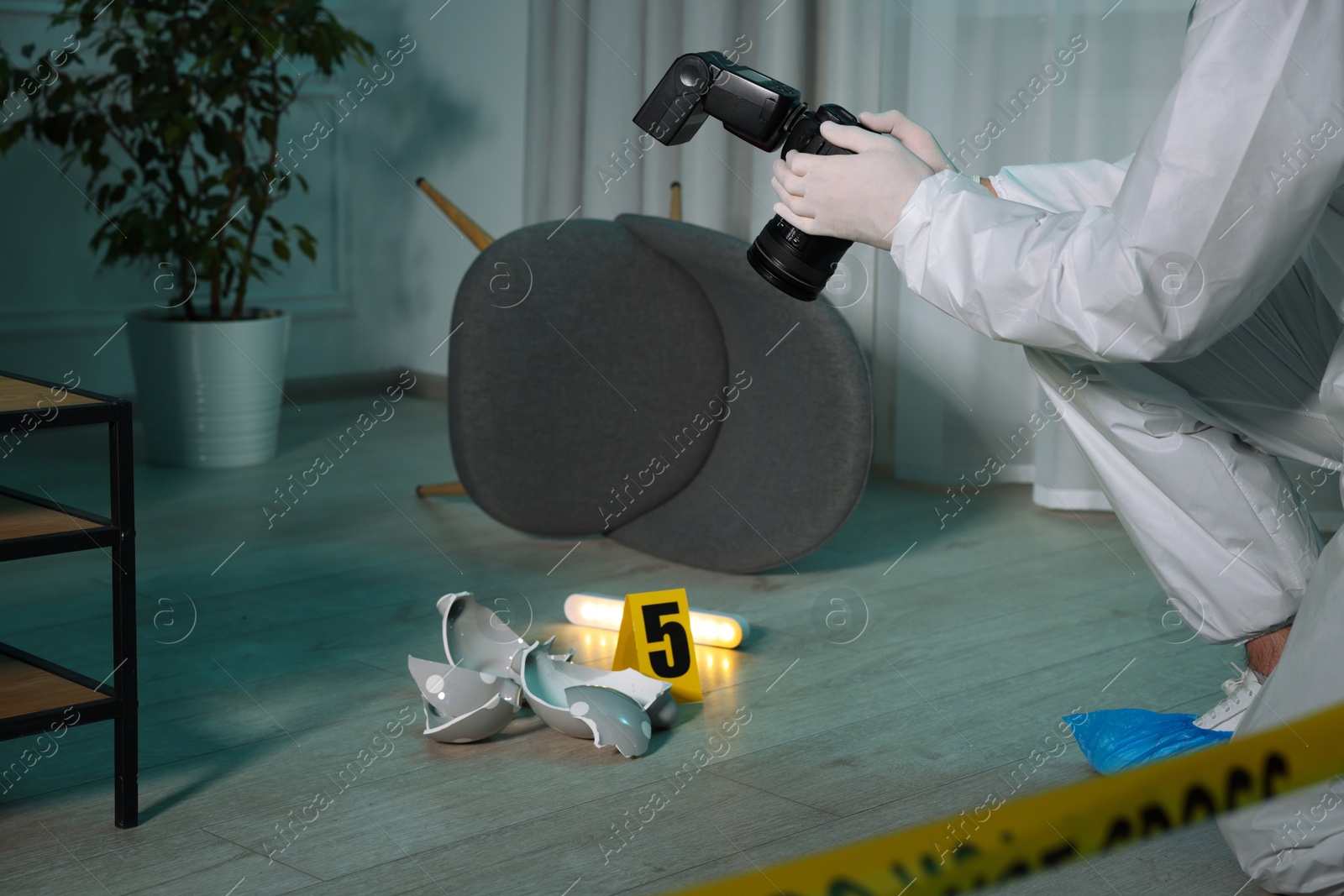 Photo of Forensic expert with camera taking photo of evidence at crime scene indoors, closeup