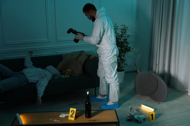 Photo of Forensic expert with camera working at crime scene and dead woman's body indoors