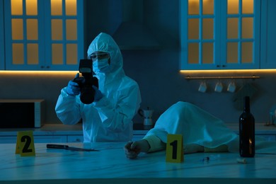 Photo of Forensic expert with camera working at crime scene and dead woman's body in dark room