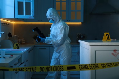 Forensic expert with camera working at crime scene in dark room