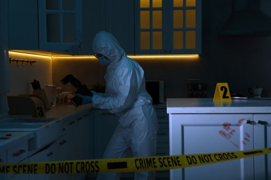 Photo of Forensic expert with camera working at crime scene in dark room