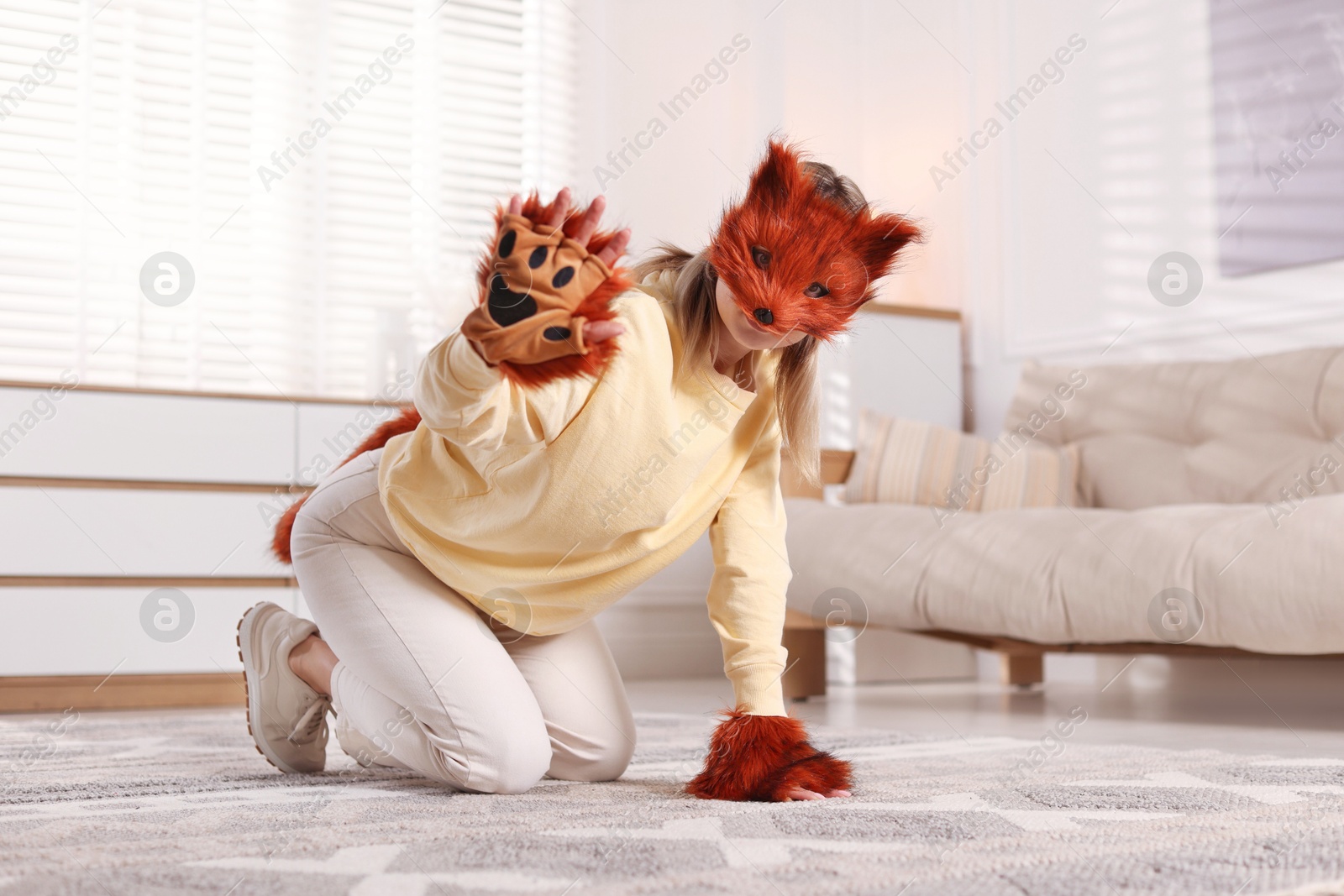 Photo of Quadrobics. Woman wearing fox mask, gloves and tail at home