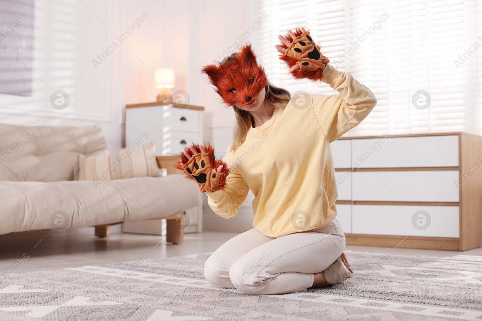 Photo of Quadrobics. Woman wearing fox mask and gloves at home