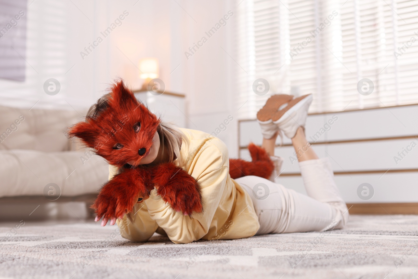 Photo of Quadrobics. Woman wearing fox mask, gloves and tail at home