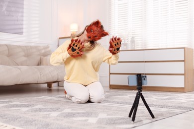 Photo of Quadrobics. Woman in fox mask and gloves recording video at home