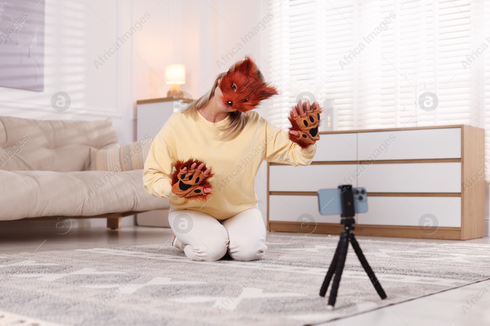 Photo of Quadrobics. Woman in fox mask and gloves recording video at home