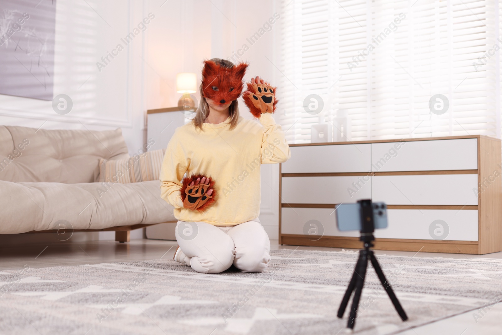 Photo of Quadrobics. Woman in fox mask and gloves recording video at home