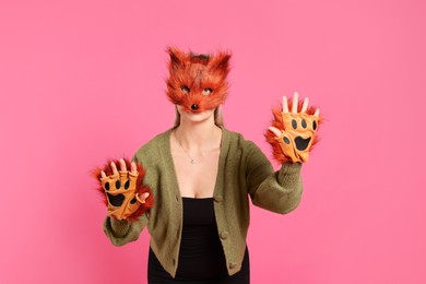 Photo of Quadrobics. Woman wearing fox mask and gloves on pink background