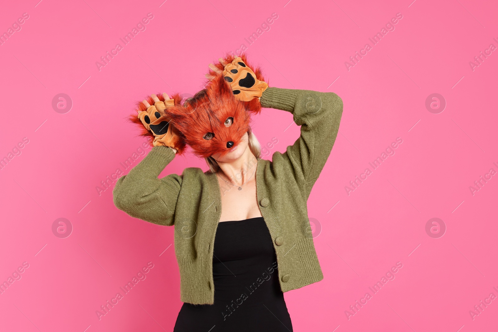 Photo of Quadrobics. Woman wearing fox mask and gloves on pink background