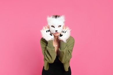 Quadrobics. Woman wearing cat mask and gloves on pink background