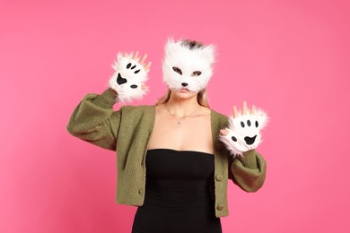 Quadrobics. Woman wearing cat mask and gloves on pink background