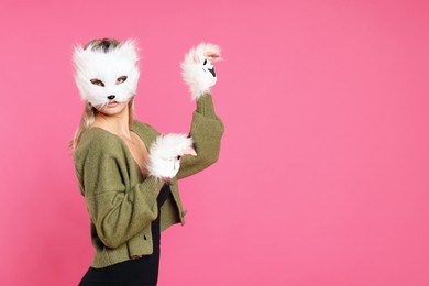 Photo of Quadrobics. Woman wearing cat mask and gloves on pink background, space for text