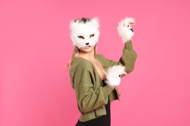 Photo of Quadrobics. Woman wearing cat mask and gloves on pink background