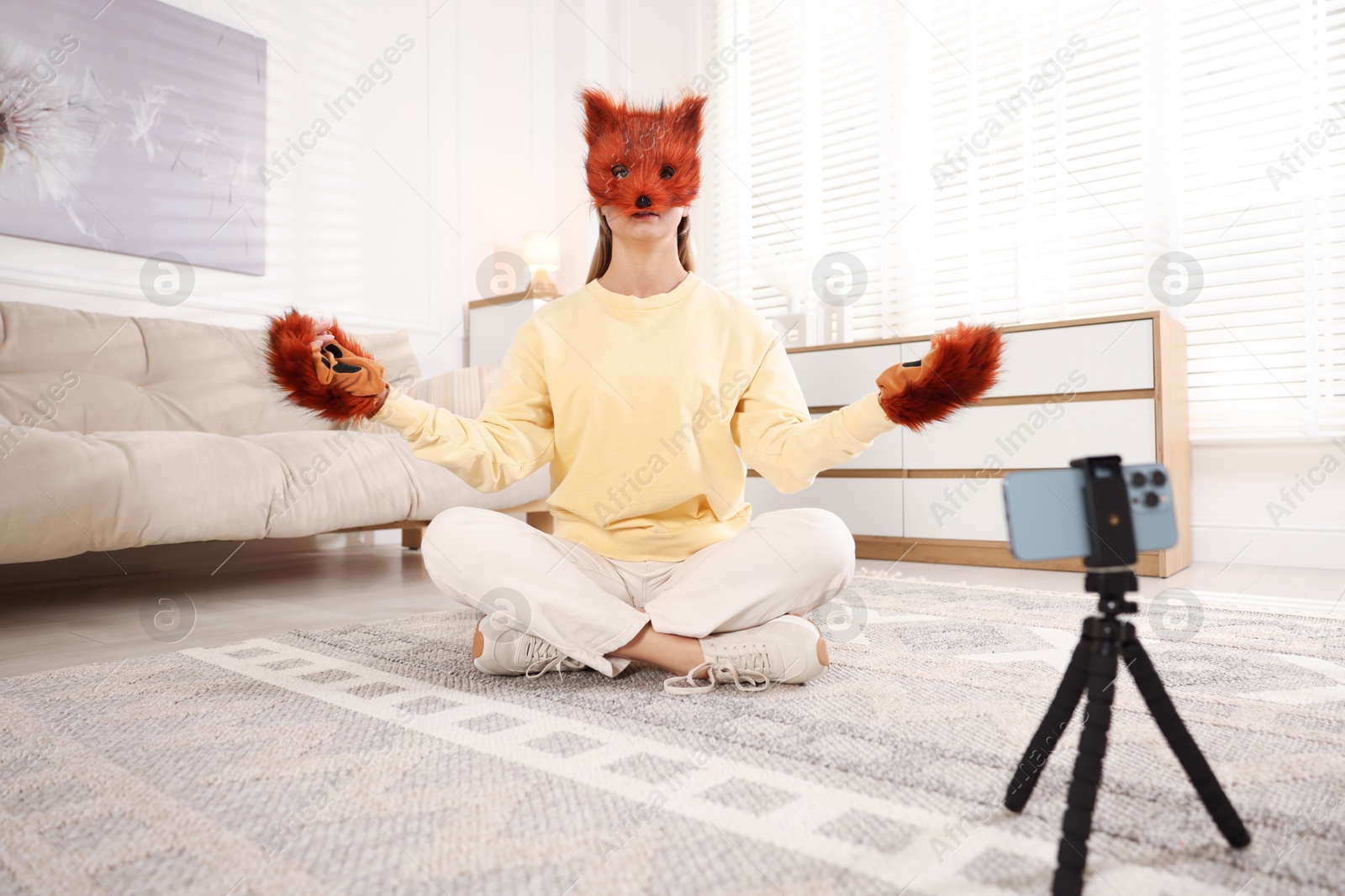 Photo of Quadrobics. Woman in fox mask and gloves recording video at home