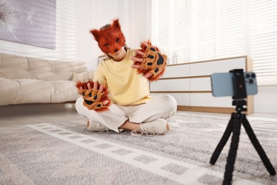 Photo of Quadrobics. Woman in fox mask and gloves recording video at home