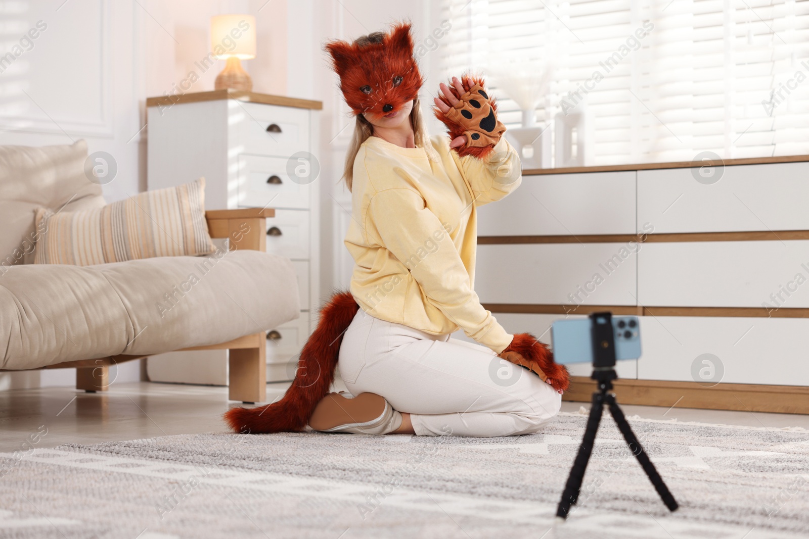 Photo of Quadrobics. Woman in fox mask, gloves and tail recording video at home