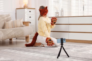 Quadrobics. Woman in fox mask, gloves and tail recording video at home