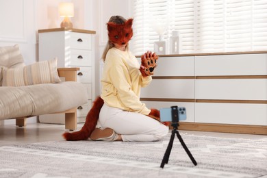 Quadrobics. Woman in fox mask, gloves and tail recording video at home