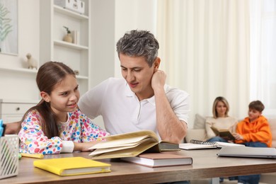 Parents and their children doing homework at home, selective focus