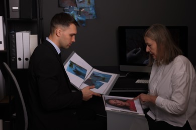 Forensic experts working with crime scene photos in office