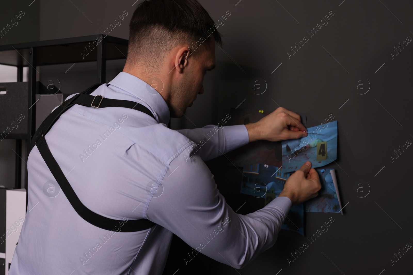 Photo of Forensic expert working with crime scene photos in office