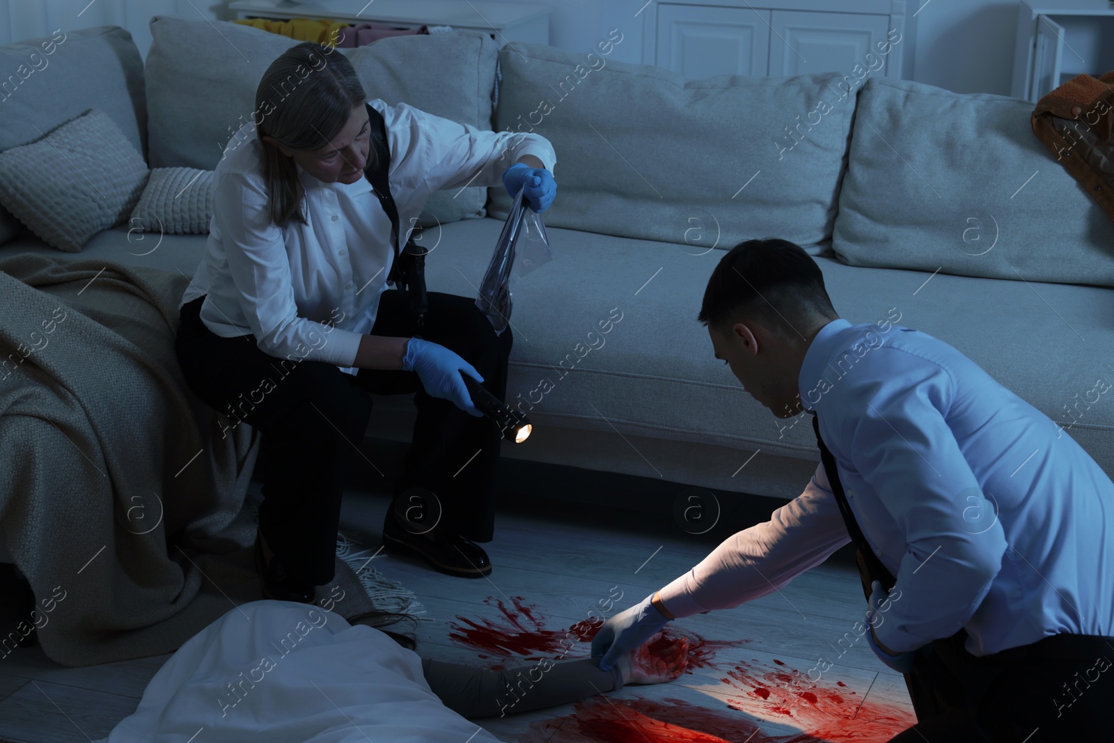 Photo of Forensic experts working at crime scene with dead woman's body indoors