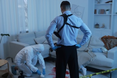 Forensic experts working at crime scene with dead woman's body indoors