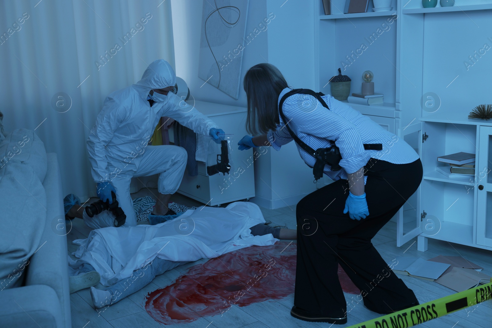 Photo of Forensic experts working at crime scene with dead woman's body indoors