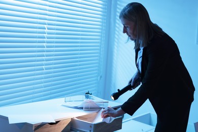 Photo of Forensic expert with flashlight working at crime scene indoors