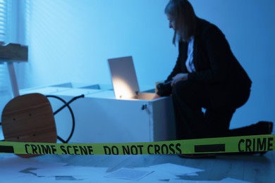 Photo of Forensic expert with flashlight working at crime scene indoors, selective focus