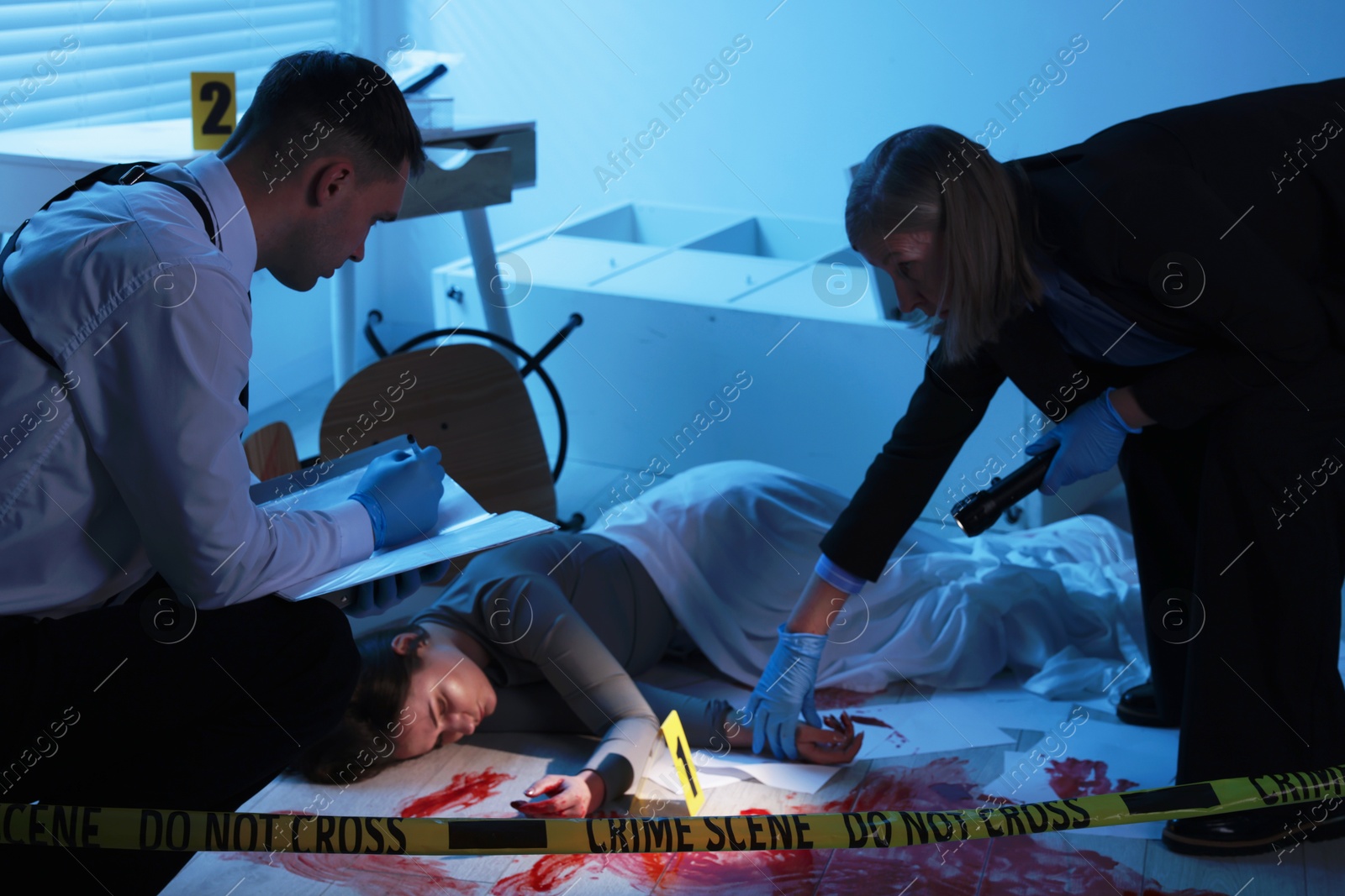 Photo of Forensic experts working at crime scene with dead woman's body indoors