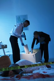 Forensic experts working at crime scene with dead woman's body indoors