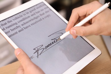 Photo of Electronic signature. Man using stylus and tablet at table, closeup