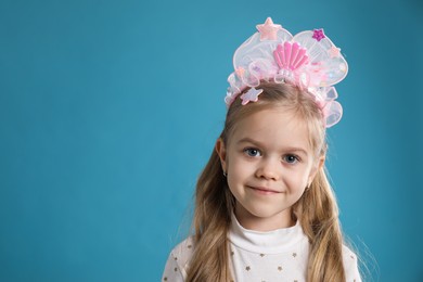 Photo of Cute little girl with beautiful headband on blue background. Space for text