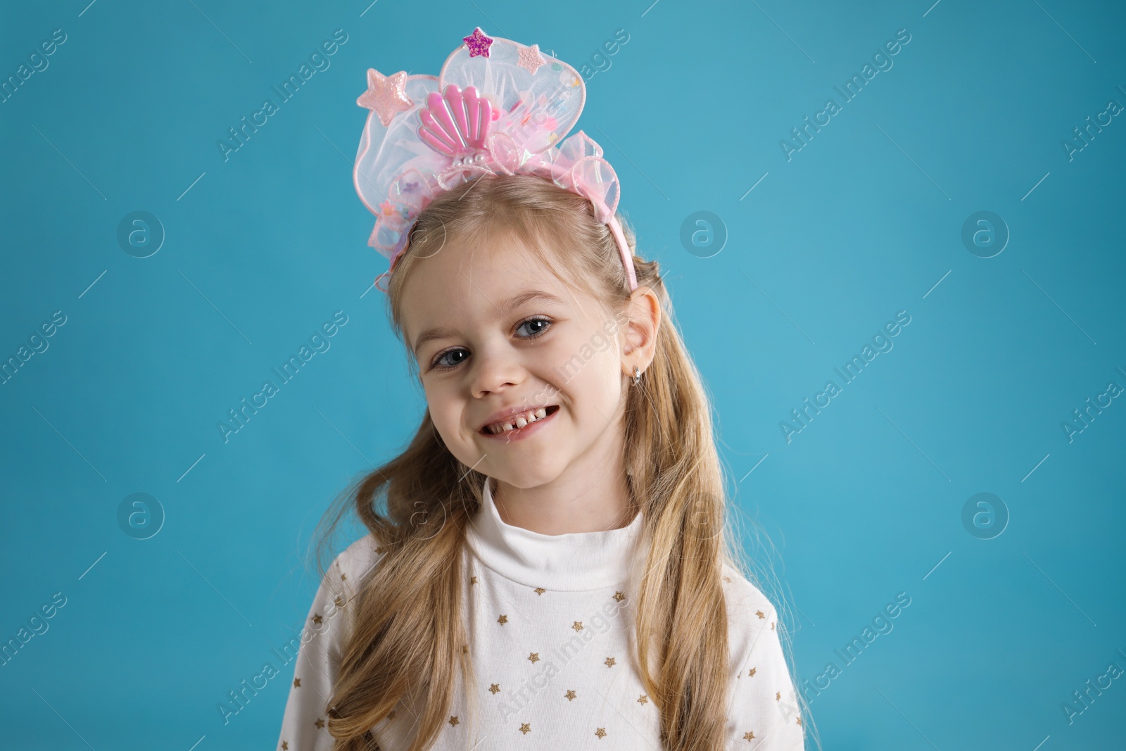 Photo of Cute little girl with beautiful headband on blue background