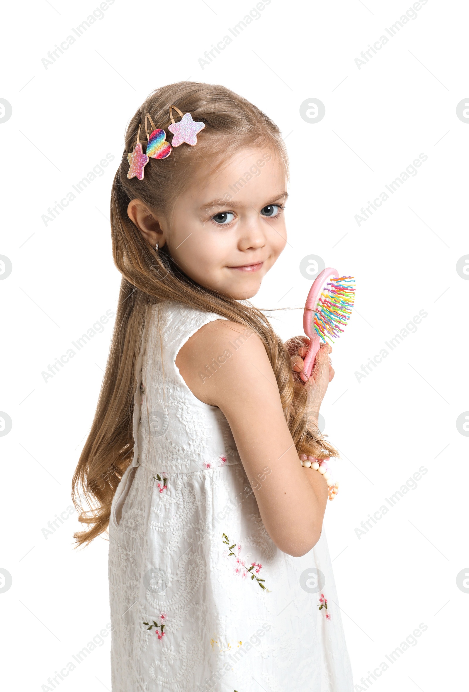 Photo of Cute little girl with beautiful hair clips and brush on white background