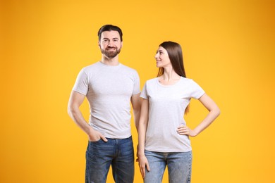 Woman and man wearing blank white t-shirts on orange background. Mockup for design