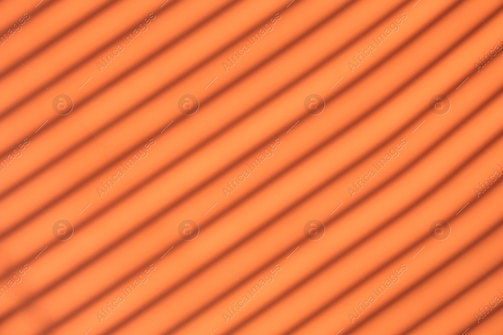 Photo of Light and shadows falling on orange background