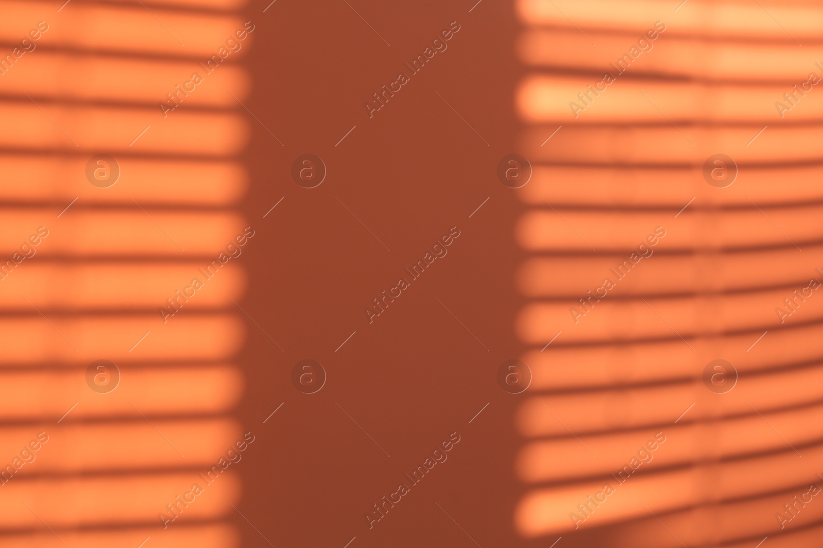 Photo of Light and shadows falling on orange background