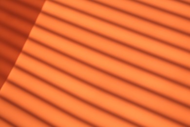 Photo of Light and shadows falling on orange background