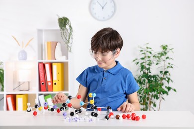 Photo of Boy making DNA structure model at desk indoors