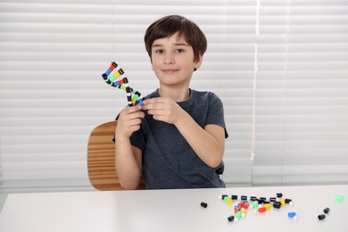 Photo of Boy with DNA structure model at desk indoors