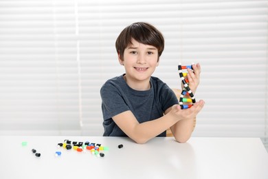 Photo of Boy with DNA structure model at desk indoors