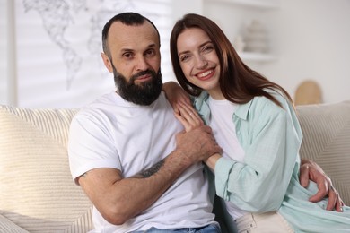 Portrait of happy daughter and father on sofa at home