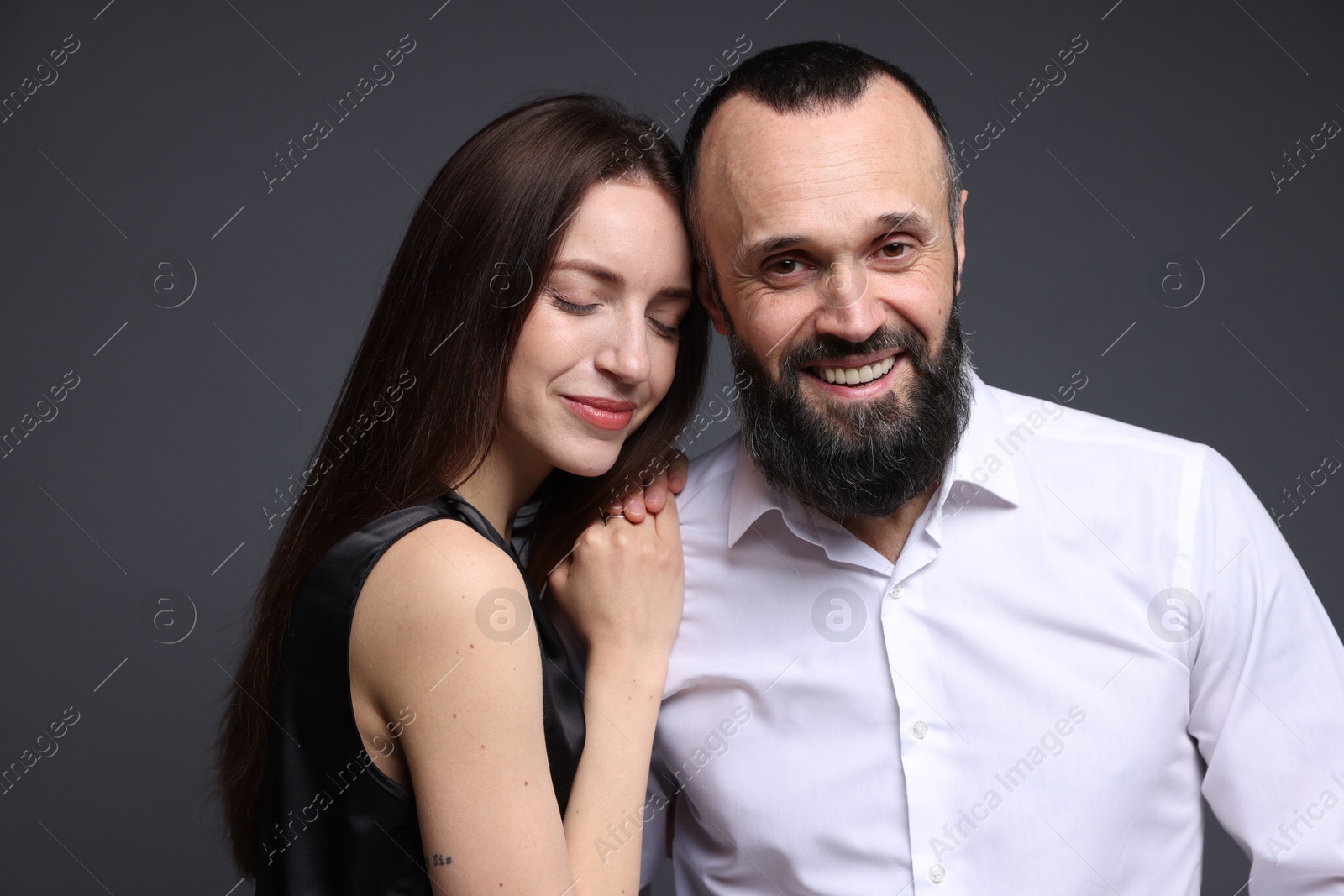 Photo of Happy daughter and father on dark grey background