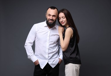 Photo of Happy daughter and father on dark grey background