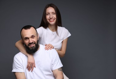 Portrait of happy daughter and father on dark grey background. Space for text